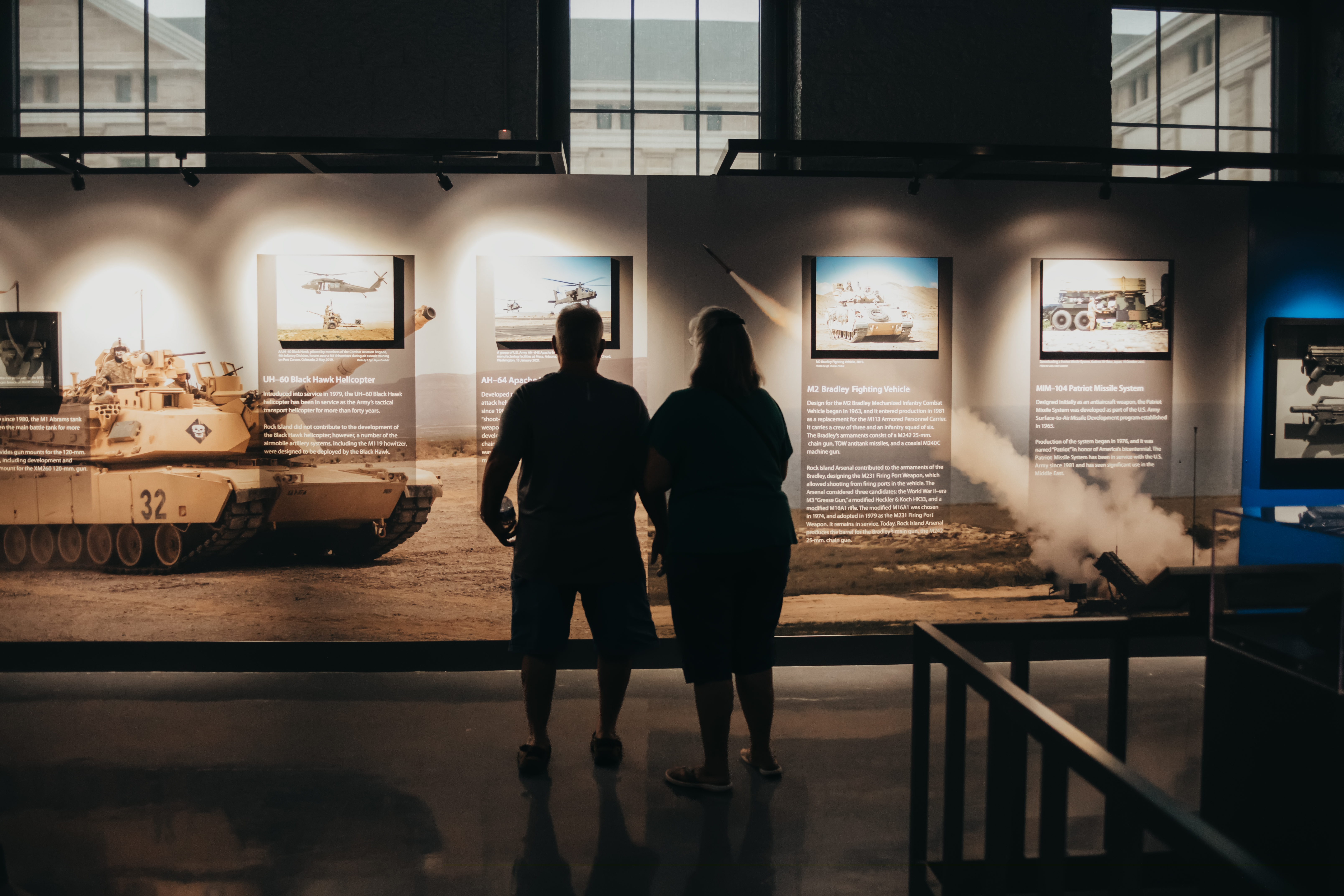 Two people looking toward a museum exhibit wall with their backs turned.